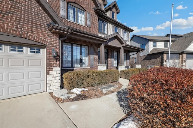 entrance to property featuring a garage and brick siding