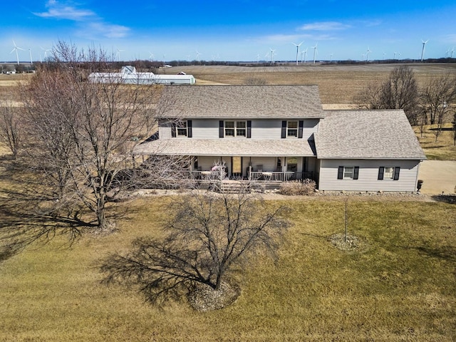 back of property with a yard, covered porch, and roof with shingles