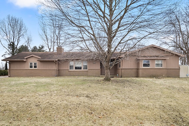 back of house with brick siding, a chimney, and a lawn