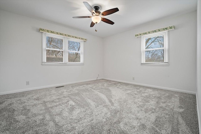 carpeted empty room with a ceiling fan, visible vents, and baseboards