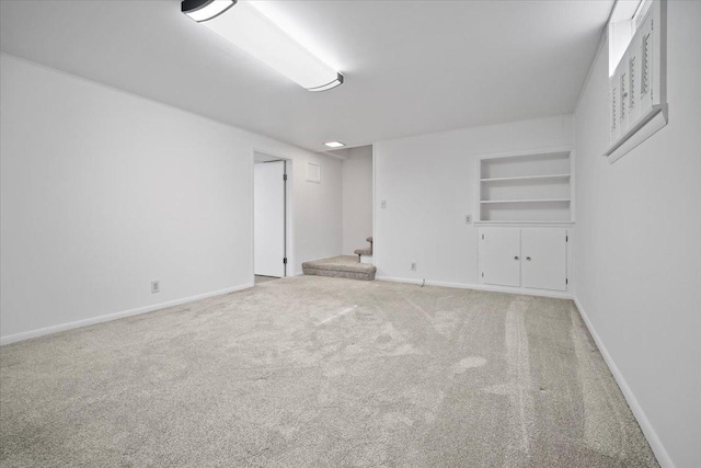 carpeted spare room featuring built in features, stairway, and baseboards