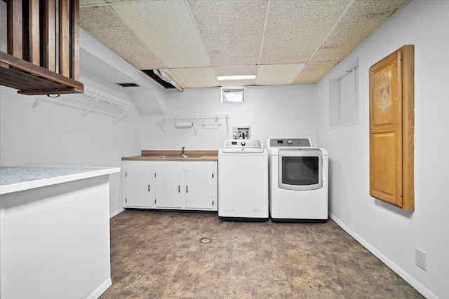 clothes washing area featuring cabinet space, baseboards, separate washer and dryer, and a sink