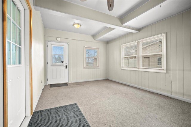 carpeted empty room with a ceiling fan, beam ceiling, and heating unit