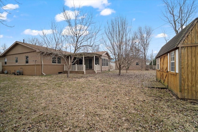 rear view of property with a yard, brick siding, and a sunroom