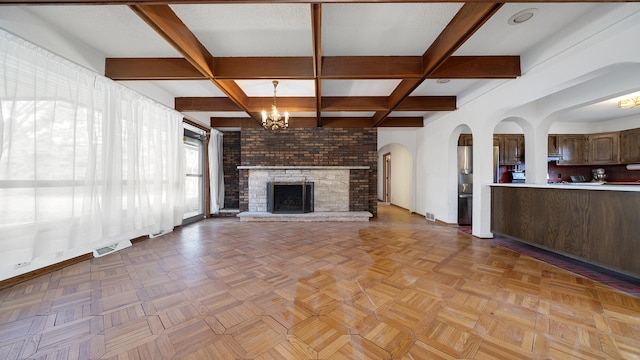 unfurnished living room featuring a notable chandelier, a fireplace, visible vents, beamed ceiling, and baseboards