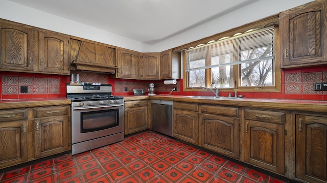 kitchen with stainless steel appliances, dark floors, a sink, and backsplash