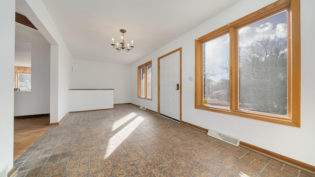 unfurnished room with baseboards, visible vents, and a notable chandelier