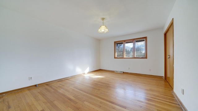 spare room with light wood-style floors, visible vents, and baseboards