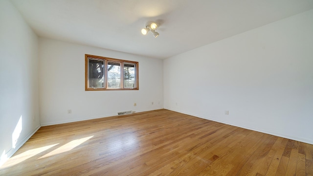 spare room with light wood-style floors, baseboards, and visible vents