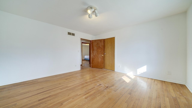 unfurnished room featuring light wood-type flooring, baseboards, and visible vents