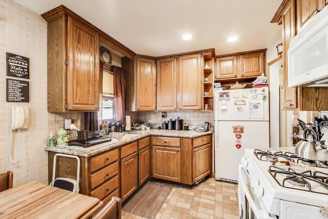 kitchen with backsplash, light stone counters, brown cabinets, white appliances, and open shelves