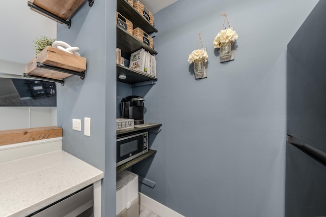 kitchen featuring light countertops, stainless steel microwave, baseboards, and open shelves