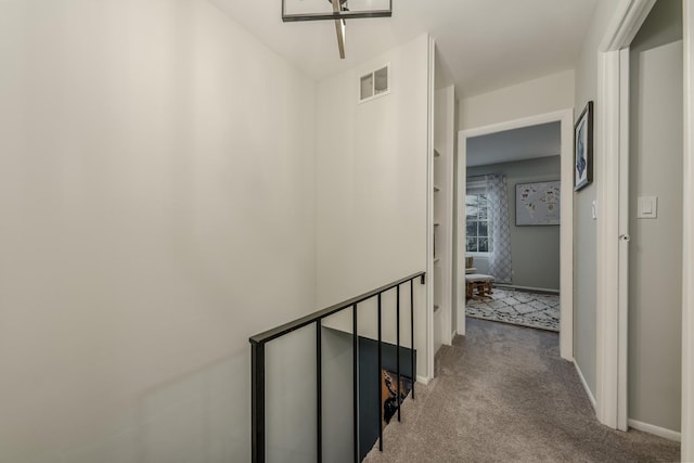 corridor with carpet, an upstairs landing, visible vents, and baseboards