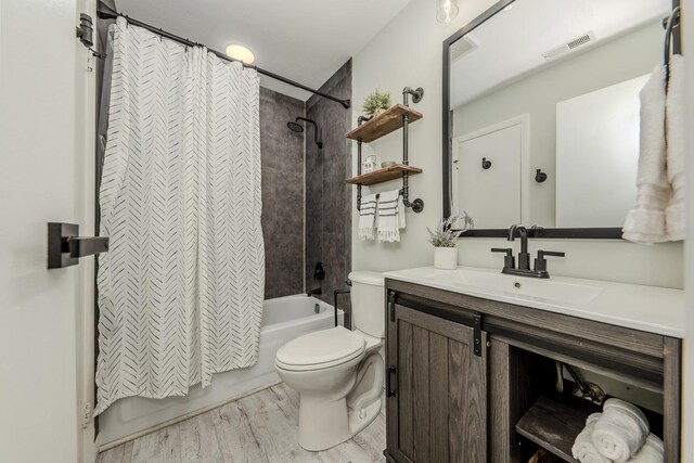 bathroom with shower / bath combo, visible vents, toilet, wood finished floors, and vanity