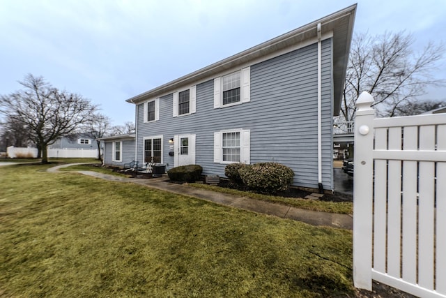 colonial-style house featuring cooling unit, fence, and a front lawn