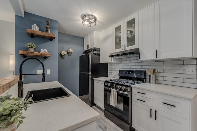 kitchen with white cabinets, decorative backsplash, appliances with stainless steel finishes, under cabinet range hood, and a sink