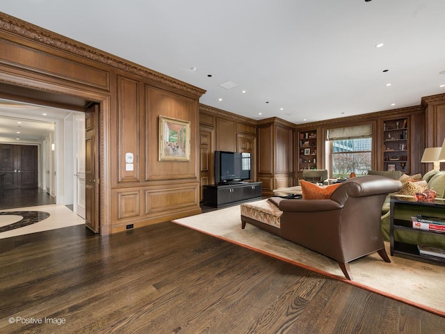 living room featuring ornamental molding, a decorative wall, wood finished floors, and recessed lighting