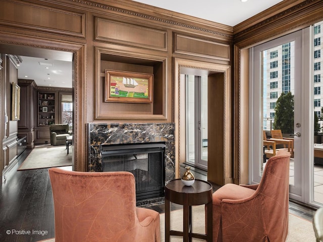 living area with built in features, a premium fireplace, ornamental molding, and wood finished floors