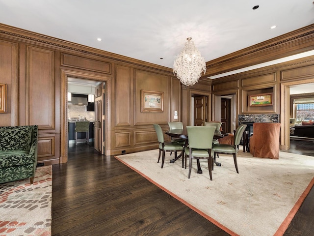 dining room featuring a chandelier, dark wood-type flooring, crown molding, and a decorative wall