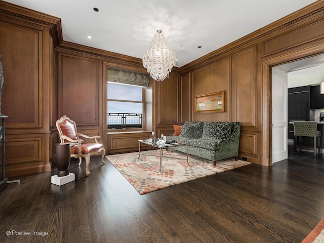 living area featuring dark wood-style floors, ornamental molding, a chandelier, and a decorative wall