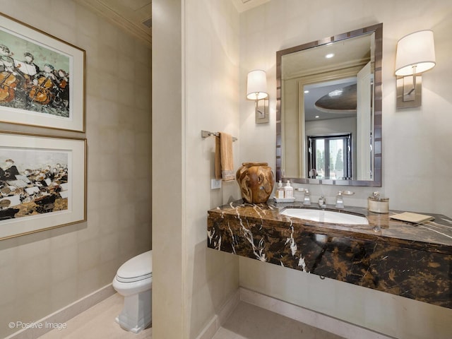 half bath featuring baseboards, a sink, and toilet