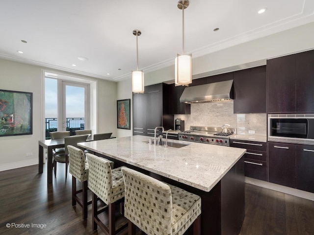 kitchen with dark wood-style flooring, a sink, ventilation hood, backsplash, and stainless steel microwave