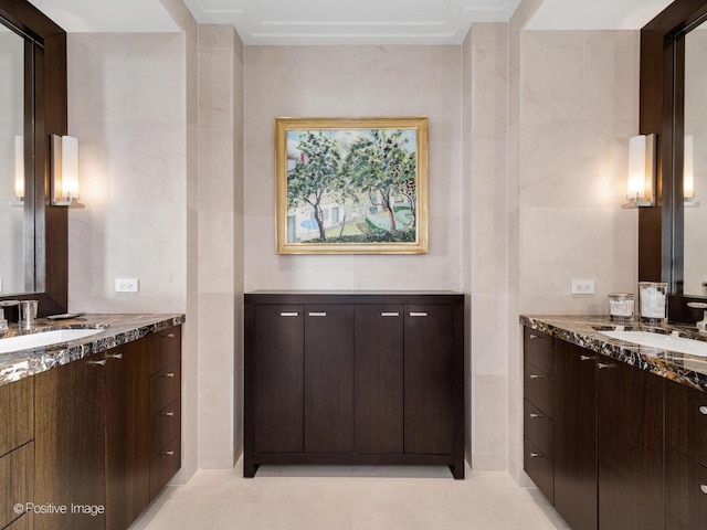 bathroom featuring two vanities, a sink, and tile walls