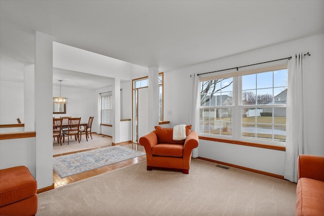 living area with carpet floors, visible vents, a notable chandelier, and baseboards