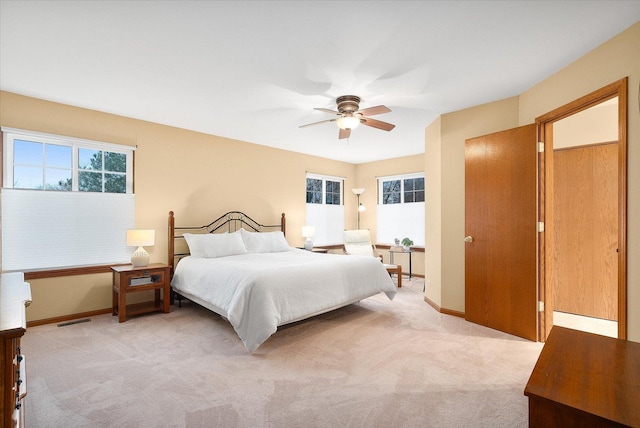 bedroom with baseboards, multiple windows, visible vents, and light colored carpet