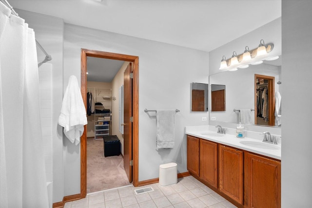 full bathroom with curtained shower, visible vents, a walk in closet, and a sink