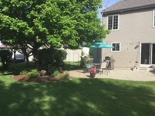 rear view of house featuring a patio area, a yard, and fence