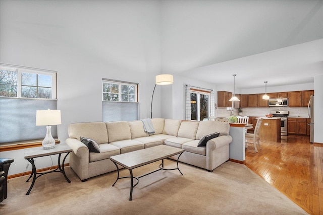 living room featuring baseboards, a towering ceiling, and a healthy amount of sunlight