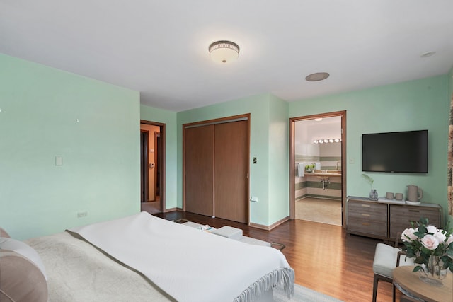 bedroom with connected bathroom, a closet, baseboards, and wood finished floors