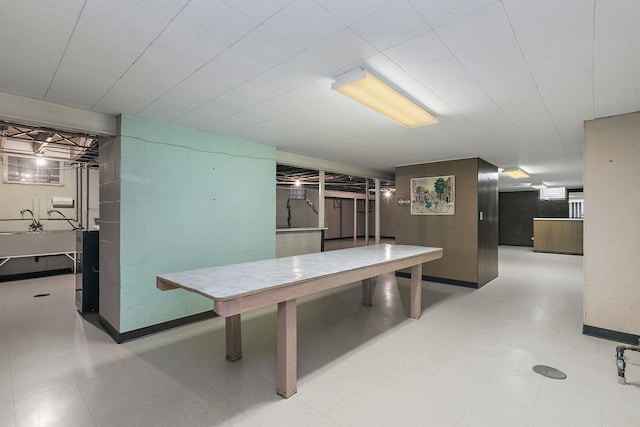 rec room with concrete block wall and tile patterned floors