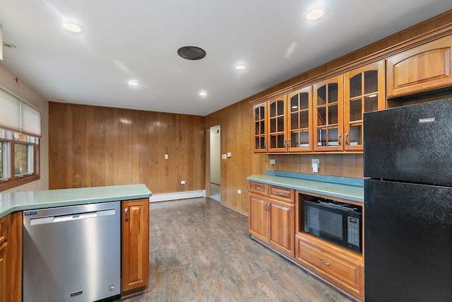 kitchen featuring black appliances, glass insert cabinets, light countertops, and wood finished floors