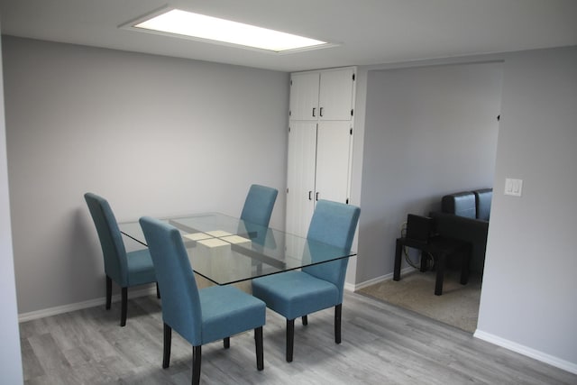 dining space with light wood-style flooring and baseboards