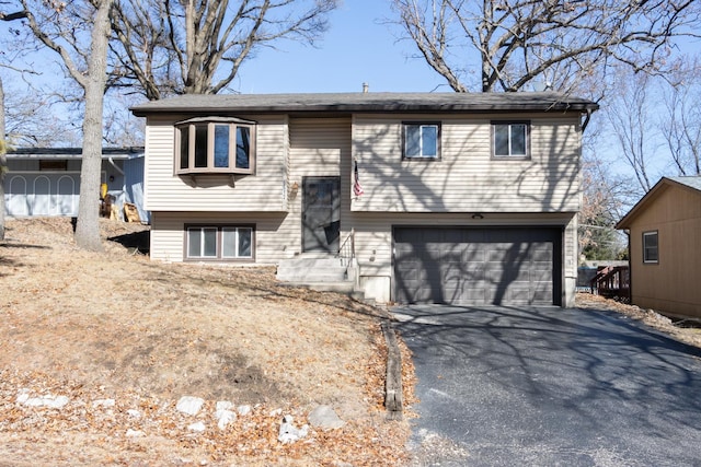 split foyer home featuring an attached garage and aphalt driveway