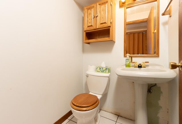 half bathroom with tile patterned flooring, baseboards, and toilet