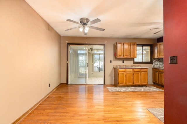 kitchen with light countertops, light wood finished floors, a ceiling fan, and baseboards