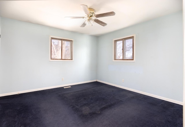 empty room with baseboards, dark colored carpet, and a ceiling fan