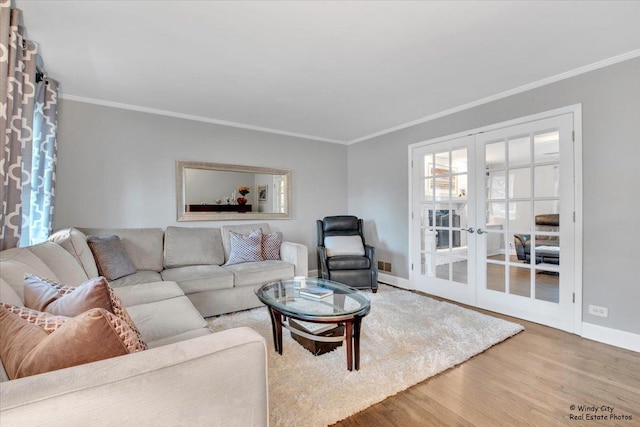 living area featuring crown molding, baseboards, wood finished floors, and french doors