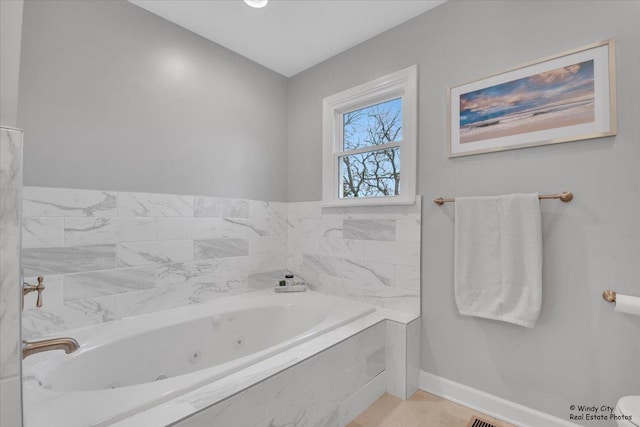 bathroom featuring a tub with jets and baseboards