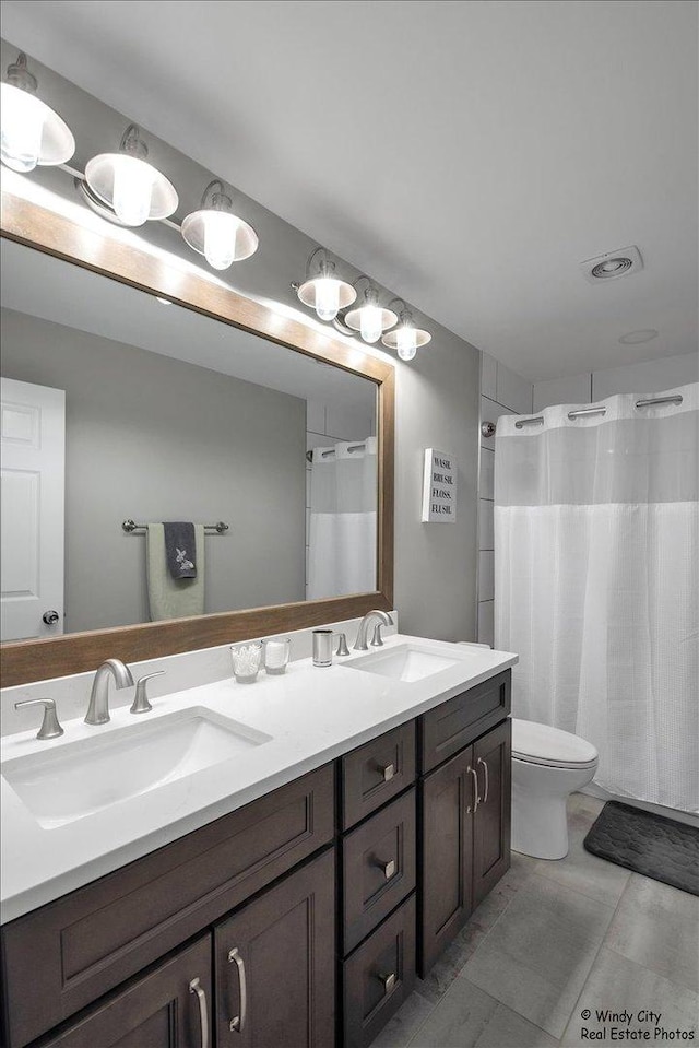 bathroom featuring visible vents, a sink, toilet, and double vanity