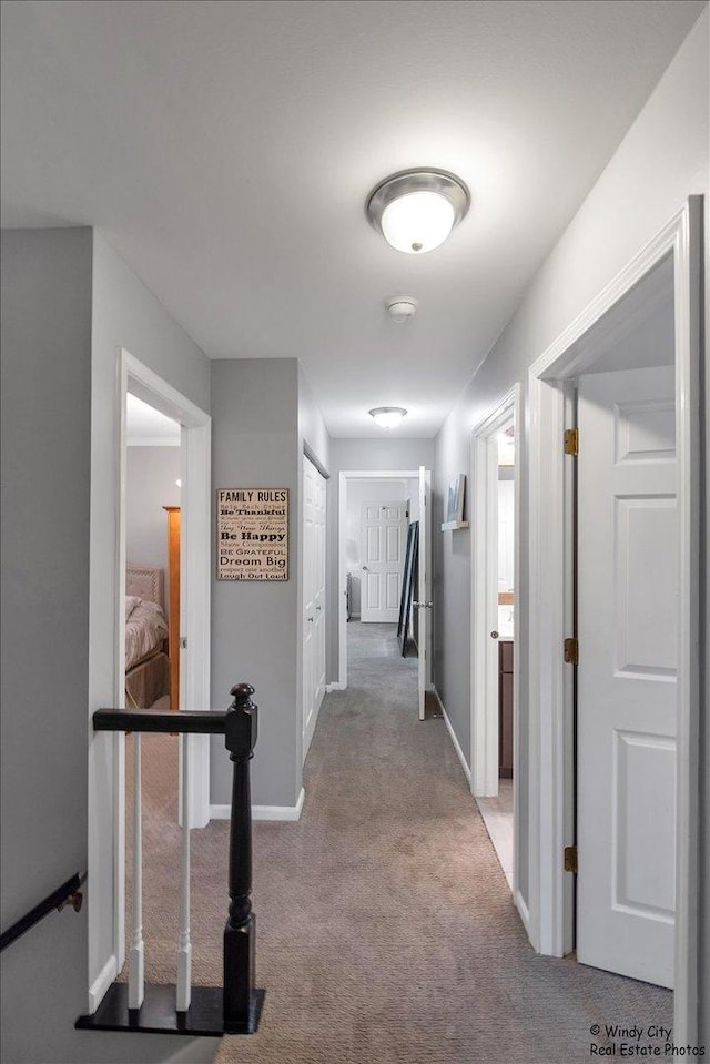 hallway featuring carpet flooring and baseboards