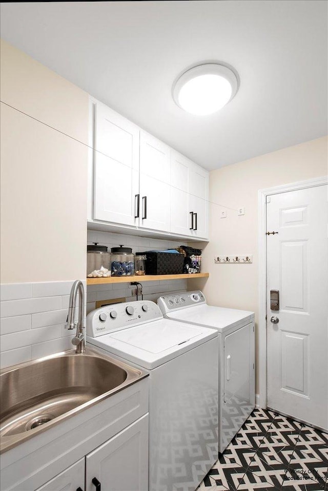 washroom featuring cabinet space, a sink, and washer and clothes dryer