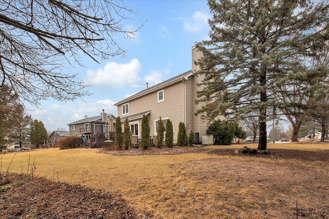 view of side of property featuring central AC, a yard, a chimney, and a wooden deck