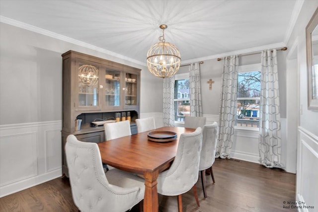 dining area featuring dark wood-style floors, crown molding, a notable chandelier, and a wainscoted wall