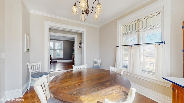 dining area featuring a chandelier, baseboards, wood finished floors, and crown molding