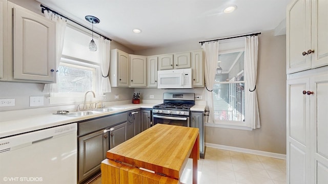 kitchen featuring gray cabinetry, baseboards, light countertops, white appliances, and a sink