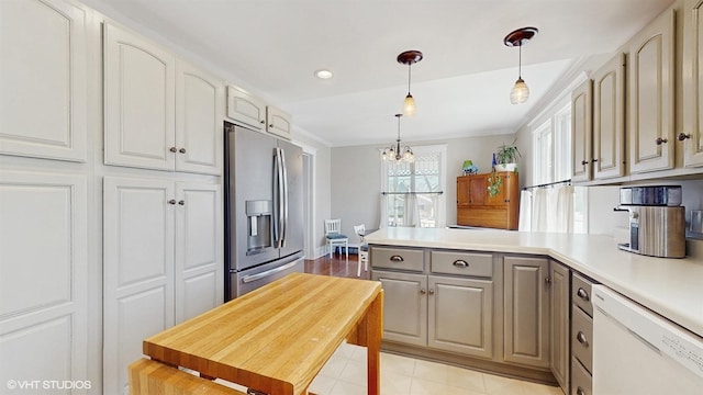 kitchen featuring light countertops, ornamental molding, a peninsula, stainless steel refrigerator with ice dispenser, and white dishwasher